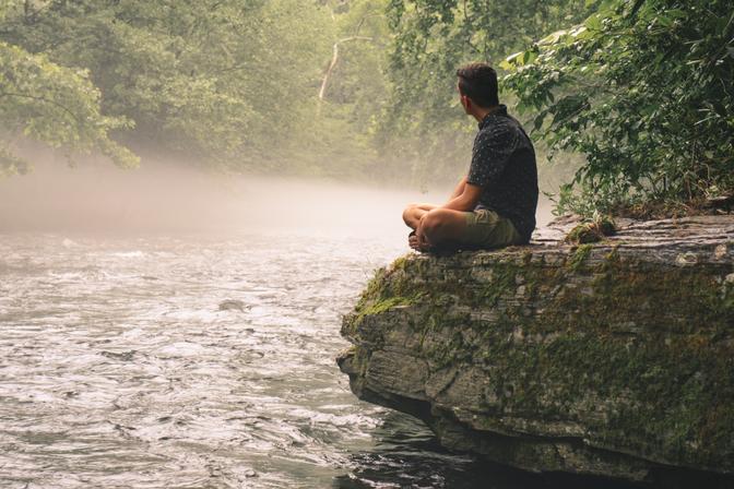 My friend Thomas sitting on a rock overlooking a river